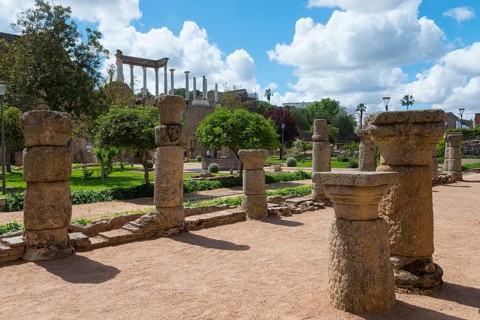 Ancient stone columns and ruins in a green garden under a sunny sky, a remnant of Roman