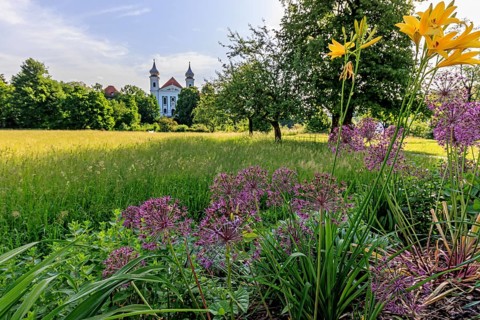 Colourful flowers in front of the church towers of a monastery against the light, spring, sunny,
