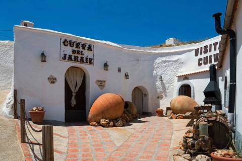 Rustic cave house with white walls and traditional decorations under a sunny sky, Cueva del Jaraiz,