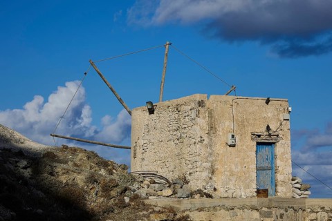 Old stone mill under clear blue sky, surrounded by clouds, Colourful mountain village, Morning