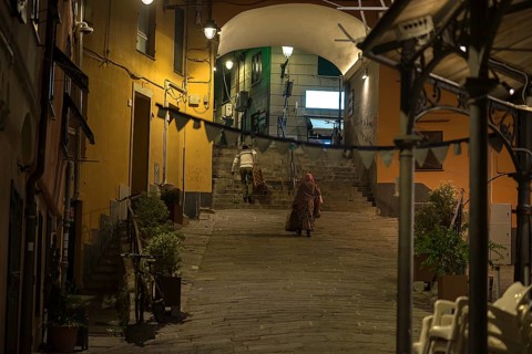 Two residents with suitcases, returning home in the evening from a trip, old town of Genoa, Italy,