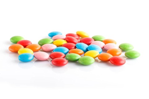 Colorful multicolored chocolate candy dragees isolated on white background. Top view, close up