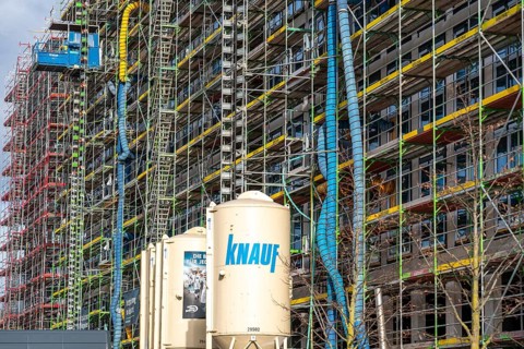 Large construction site, scaffolded shell of an office building complex, air hoses for construction