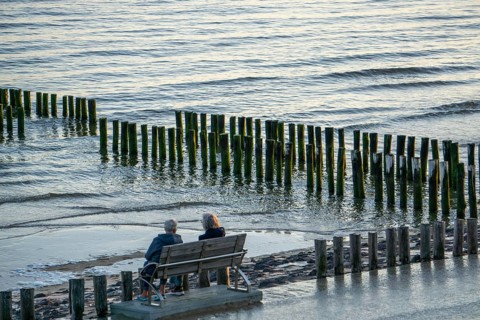 Two elderly woman on a bench on the beach, at high tide, breakwater, Netherlands