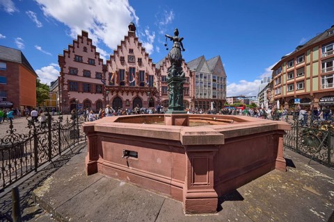 Fountain of Justice and Römer Town Hall on the Römerberg under a blue sky with cumulus clouds in