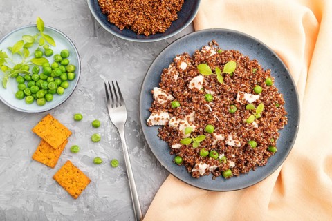 Quinoa porridge with green pea and chicken on ceramic plate on a gray concrete background and