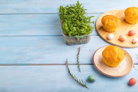 Homemade cakes with chocolate eggs and chrysanthemum microgreen on a blue wooden background. side