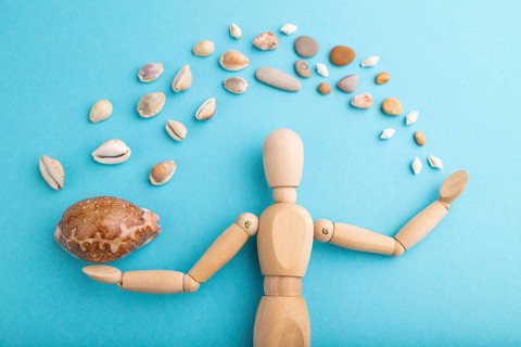 Wooden mannequin juggling sea shells on blue pastel background. close up, isolated, travel,