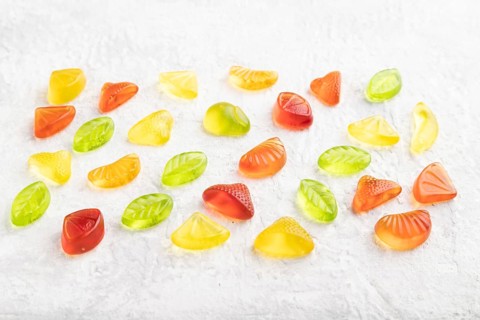 Various fruit jelly candies on gray concrete background. side view, close up