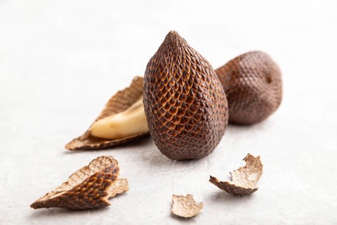 Salak or snake fruit on gray concrete background. Side view, close up, selective focus. Tropical,