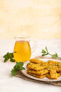 Traditional iranian dessert sohan with glass of green tea on a gray concrete background and linen