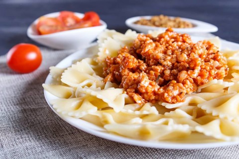 Farfalle bolognese pasta with minced meat on black wooden background. close up, selective focus