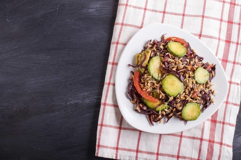 Vegetarian salad of purple cabbage, germinated wheat, tomatoes and avocado on linen tablecloth,