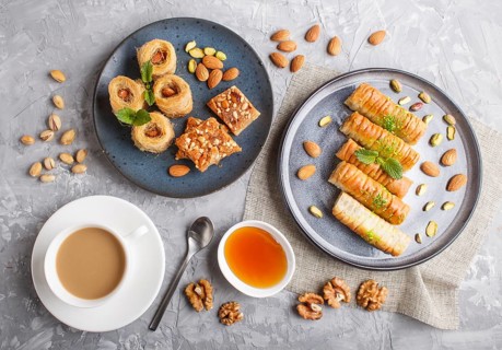Set of various traditional arabic sweets: baklava, kunafa, basbus in ceramic plates on a gray