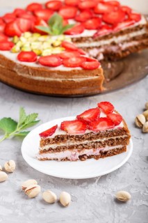 Homemade cake with yoghurt cream, strawberry, pistachio and a cup of coffee on a gray concrete
