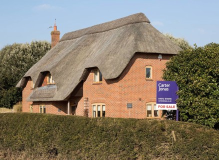 Thatched country cottage for sale with Carter Jonas estate agent sign outside, Alton Priors,