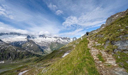 Mountaineer on hiking trail in picturesque mountain landscape, mountain peak with snow and glacier
