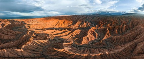 Panorama, landscape of eroded hills at Lake Issyk Kul, badlands at sunset, mountain peaks of the