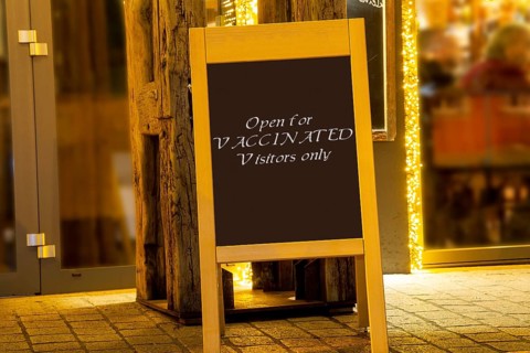 Street sign in front of a restaurant with the inscription Open for Vaccinated Visitors only