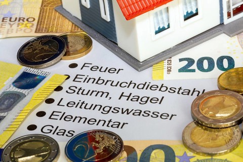 Symbolic image of building insurance: close-up of contract documents, a model house, euro banknotes