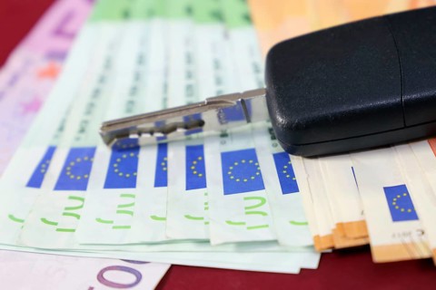 Euro banknotes and car keys as a symbol for car costs