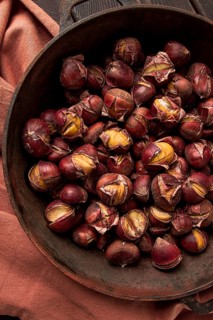 Roasted chestnuts, in an iron pan, wooden table, top view, no people, rustic style