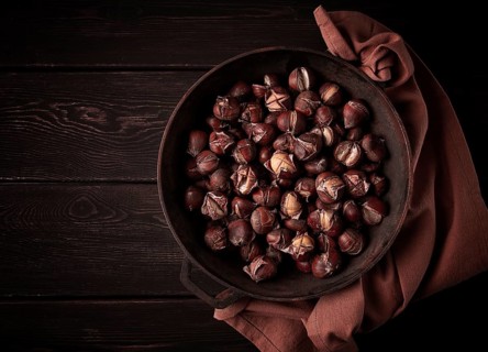 Roasted chestnuts, in an iron pan, wooden table, top view, no people, rustic style