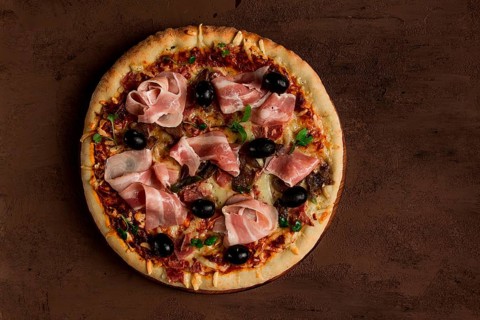 Pizza with prosciutto and mushrooms, bacon, olives, homemade, top view, no people