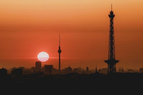 The sunrise emerges behind the city skyline with the television tower and the radio tower in