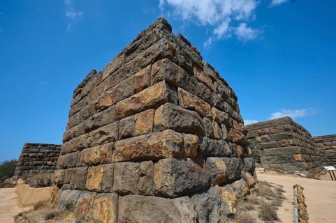 Detailed view of a corner of an ancient ruined wall in an arid landscape under a clear blue sky,