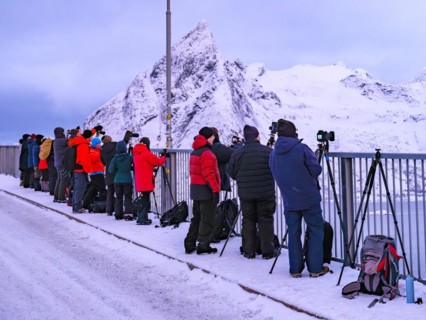 Photographers at the famous photo spot of Hamnoy in the morning light, snow-covered mountains in