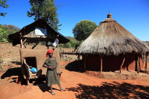 South Ethiopia, Benna people, house, hut, woman in front of her round hut in a Benna village,
