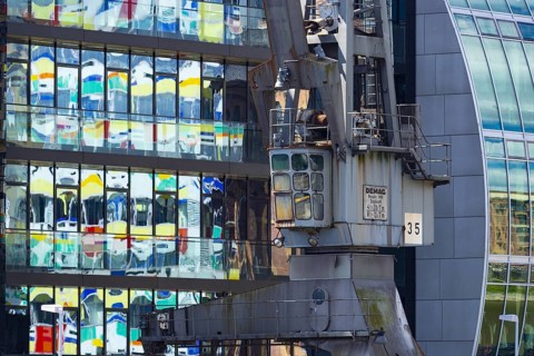 Old crane in front of the glass façade of an office building, reflecting the Colorium high-rise,