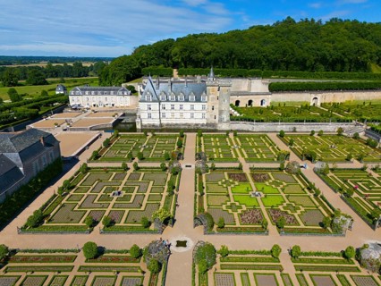 Aerial view of a castle with symmetrical, formal gardens characterised by green hedges and