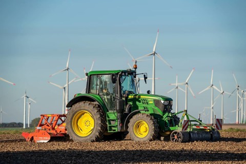 Farmer working in the fields, with a tractor, wind farm above the village of Lichtenau,