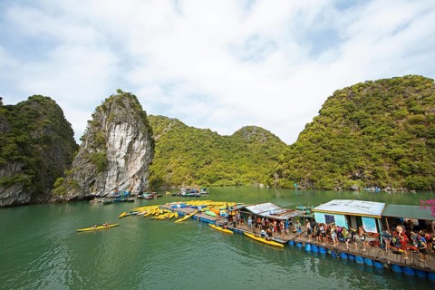 Holidaymakers queue for a kayak on a jetty, behind the karst rocks in Lan Ha Bay, Halong Bay,