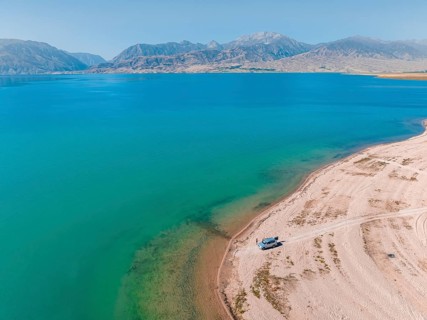 Tourists at the lake with car, aerial view, erosion landscape at the river Naryn, Toktogul