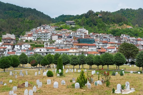 A peaceful cemetery in the foreground with a settlement on the hill in the background on a cloudy