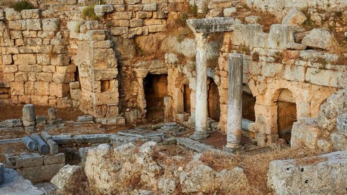 Ancient ruins with column remains and undergrowth in the evening sun, Peirene Fountain,