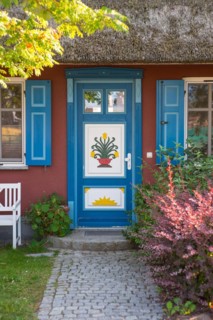 Colourful front door of a thatched roof house with decorative carving and painting, flower motif,