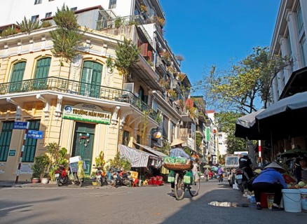 Vietnamese saleswoman with conical hat pushing her bicycle through the Old Quarter, Hanoi, Vietnam,