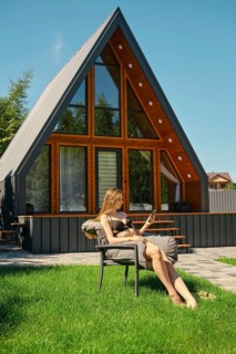 Slender woman lounging in a chair, enjoying the sun with a smartphone in her hand. She is scrolling