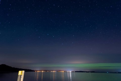 Northern lights (aurora borealis) shine on a starry night over Lake Plau, Ganzlin,