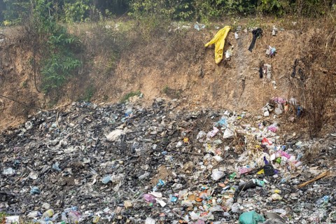 Coking rubbish dump, rubbish pit with waste and plastic rubbish, karst landscape near Vang Vieng,