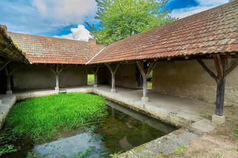 Washhouse in Montaigu-le-Blin village features a grassy basin, Allier. Auvergne-Rhone-Alpes,