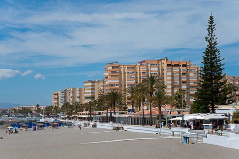 Beach promenade with high residential buildings and palm trees, summer sky, Torrox, Málaga