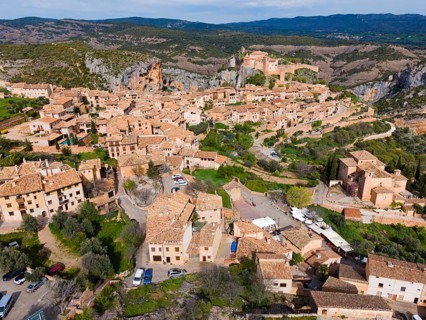 A charming village with historic tiled roofs and fortified buildings, nestled in the mountains,