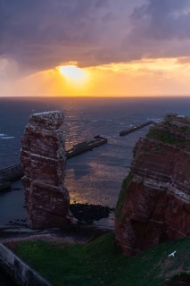 Red sandstone cliff with Lange Anna on the offshore island of Heligoland, mole as protection