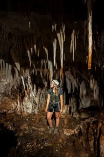 Young woman with helmet and headlamp, tourist between stalactites and stalagmites in a stalactite