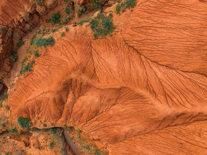 Eroded mountain landscape, top-down, canyon with red and orange rock formations, aerial view,